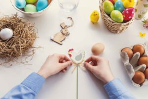 Zwei bastelnde Hände basteln Osterdekorationen
